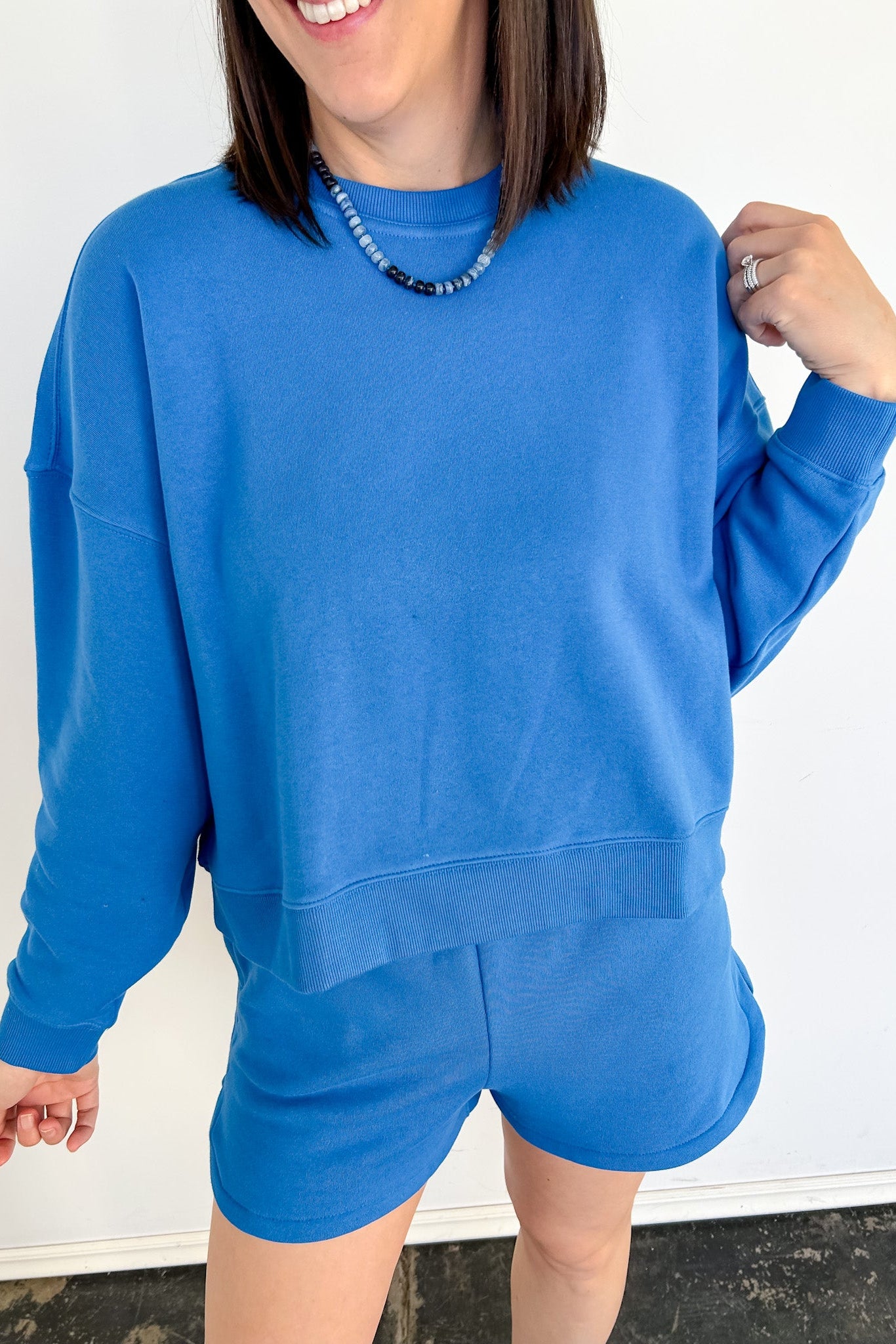 Person wearing a blue sweatshirt and shorts set against a white background