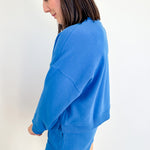 Person wearing a blue sweatshirt and shorts set against a white background