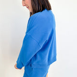 Person wearing a blue sweatshirt and shorts set against a white background