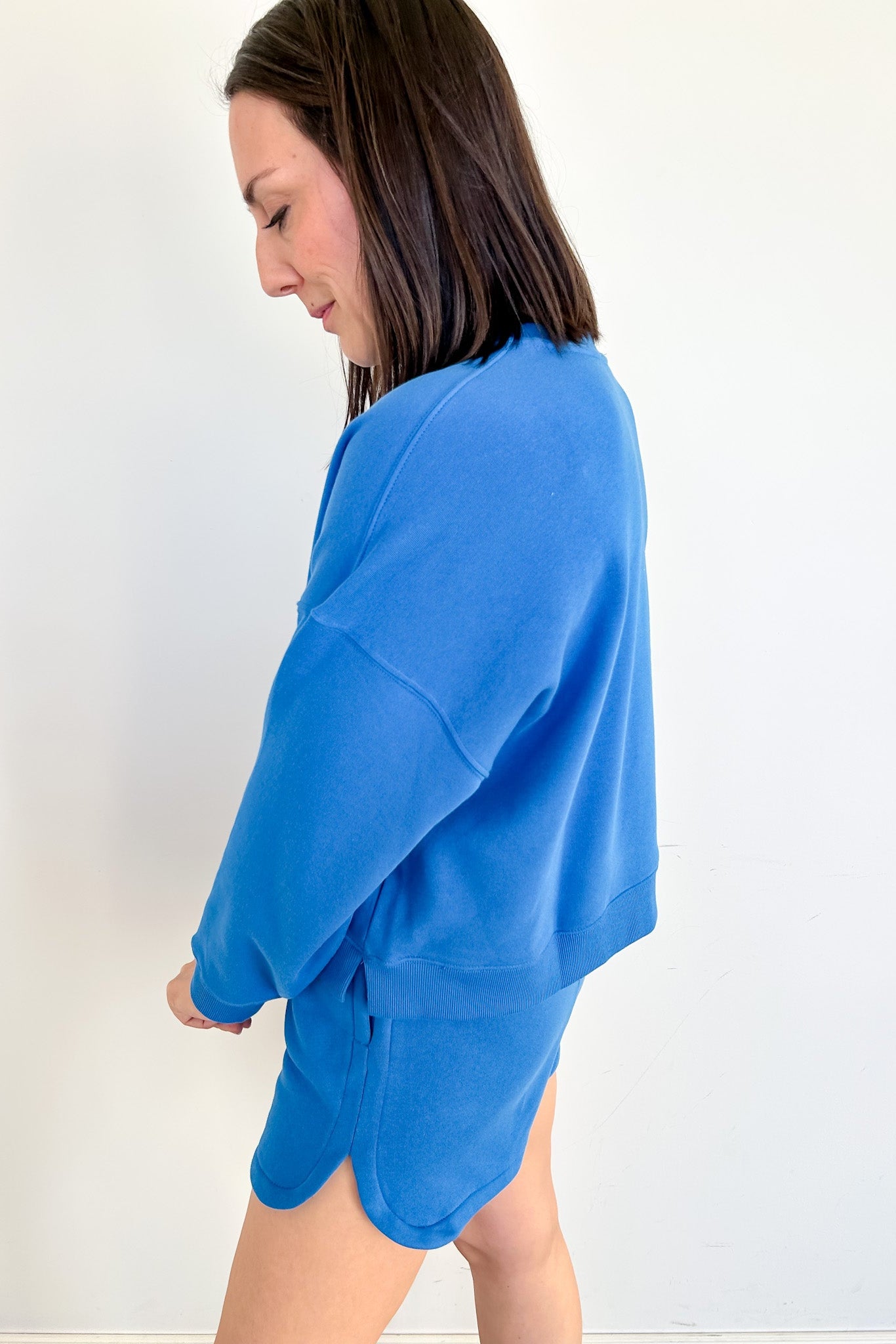 Person wearing a blue sweatshirt and shorts set against a white background