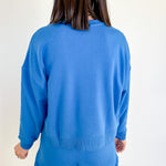 Person wearing a blue set facing a white wall