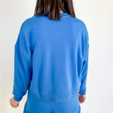 Person wearing a blue set facing a white wall