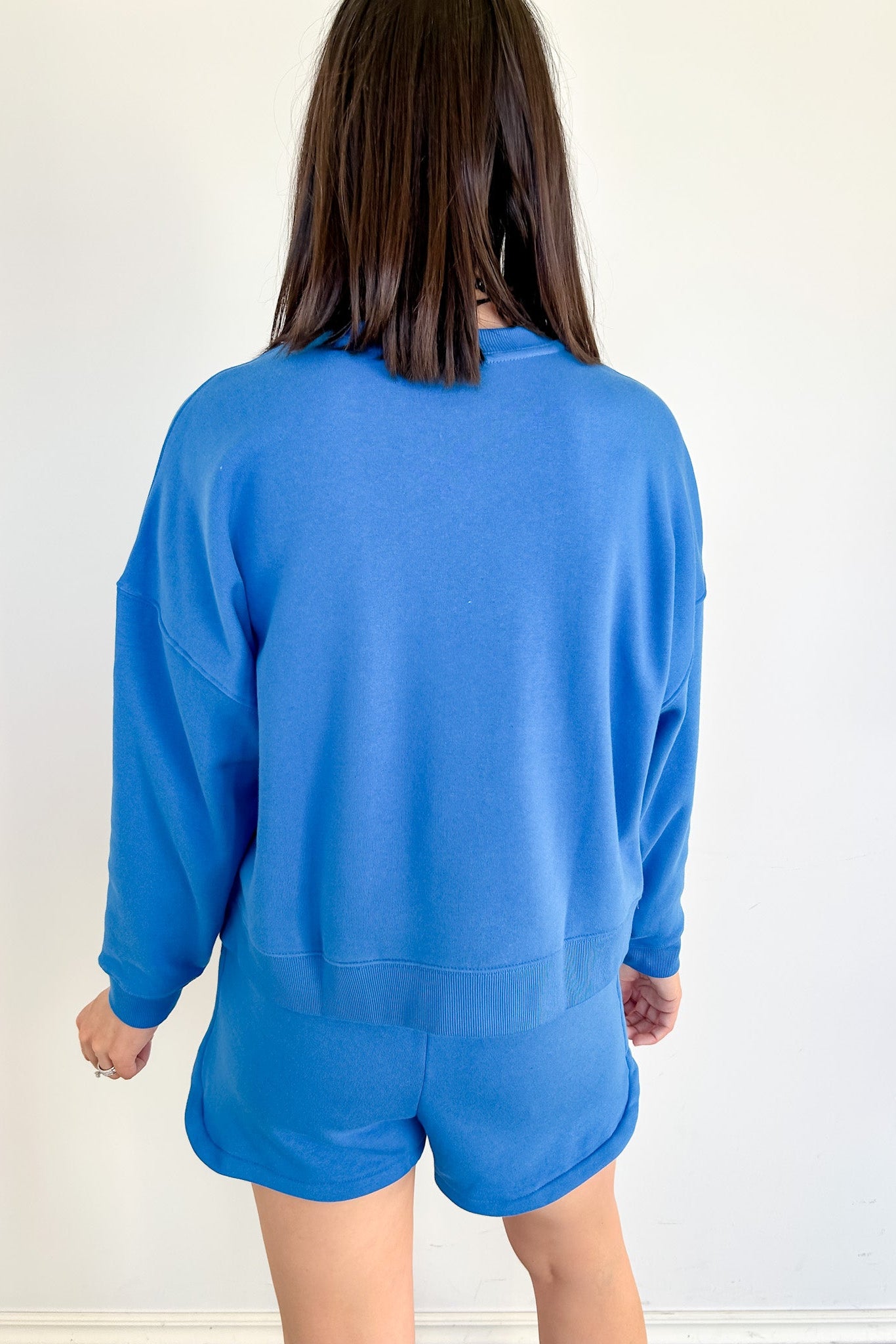 Person wearing a blue set facing a white wall