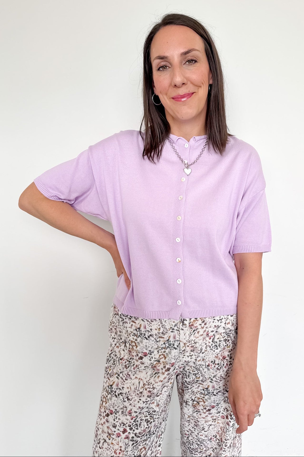 Woman wearing a light purple shirt and patterned pants against a white background