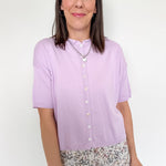 Woman wearing a light purple shirt with floral pants on a white background