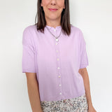 Woman wearing a light purple shirt with floral pants on a white background