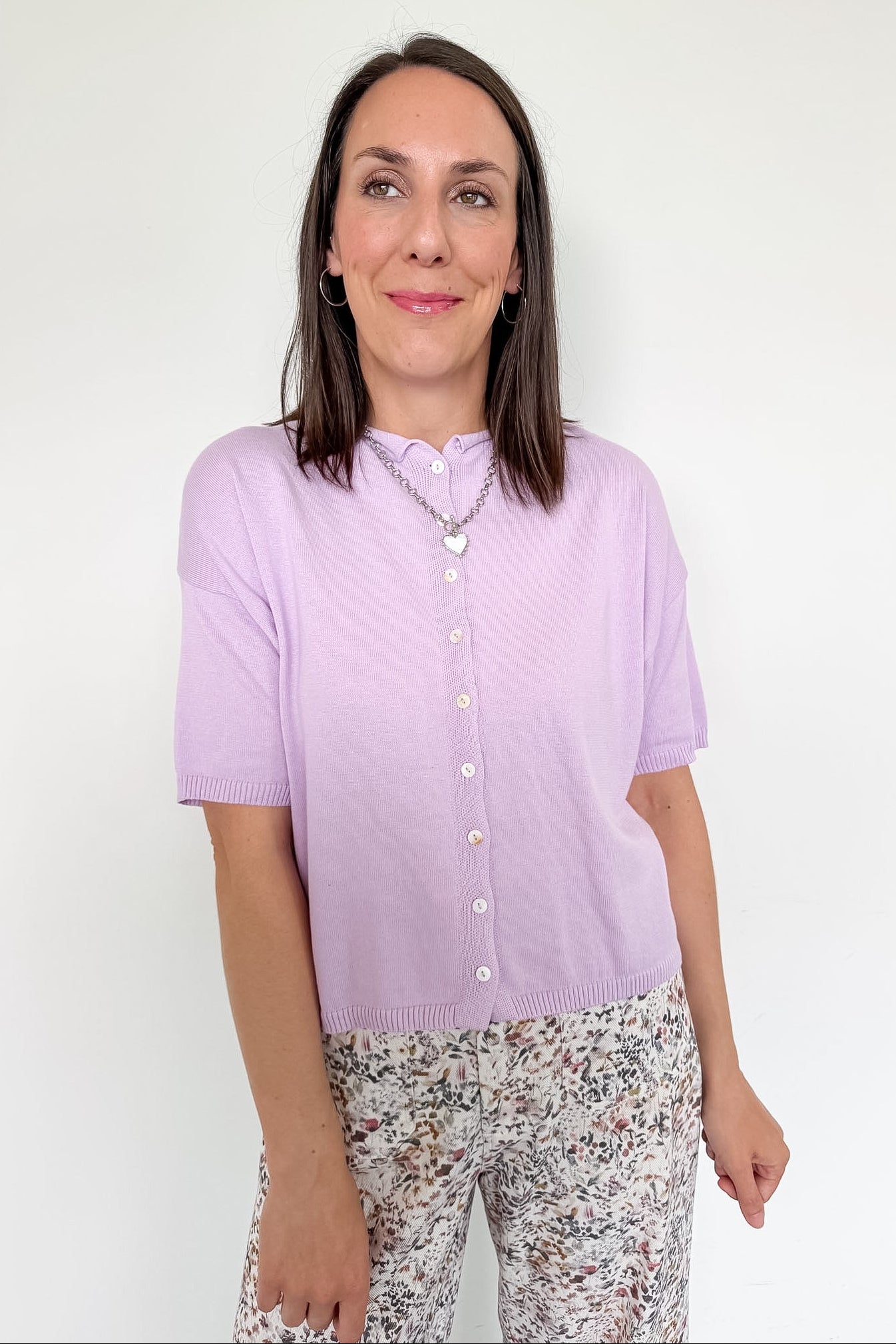 Woman wearing a light purple shirt with floral pants on a white background