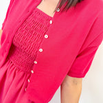 Person wearing a bright pink dress with a matching cardigan on a white background