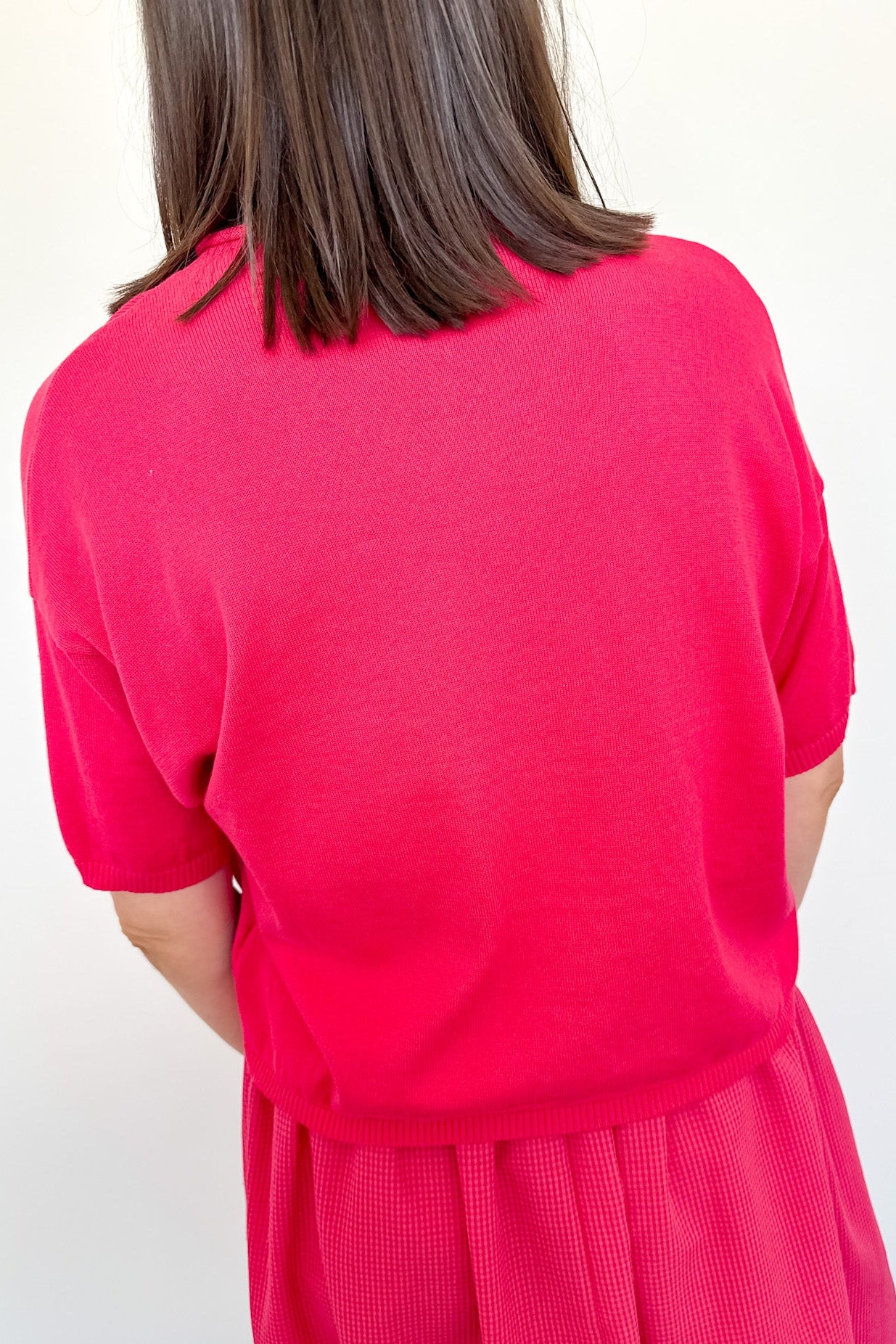 Person wearing a bright pink dress against a white background