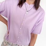 Woman wearing a light purple cardigan with a white background