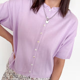 Woman wearing a light purple cardigan with a white background