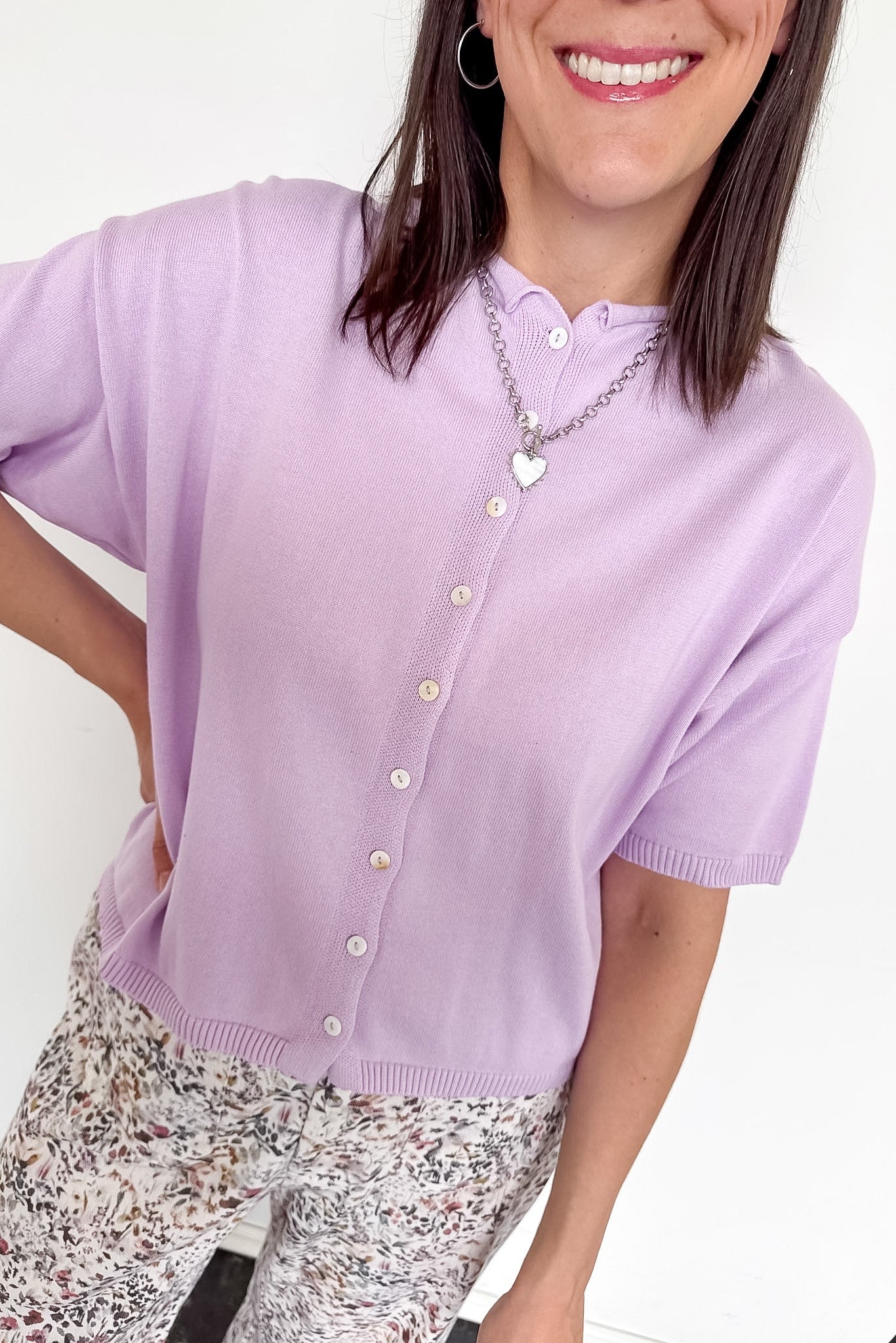 Woman wearing a light purple cardigan with a white background