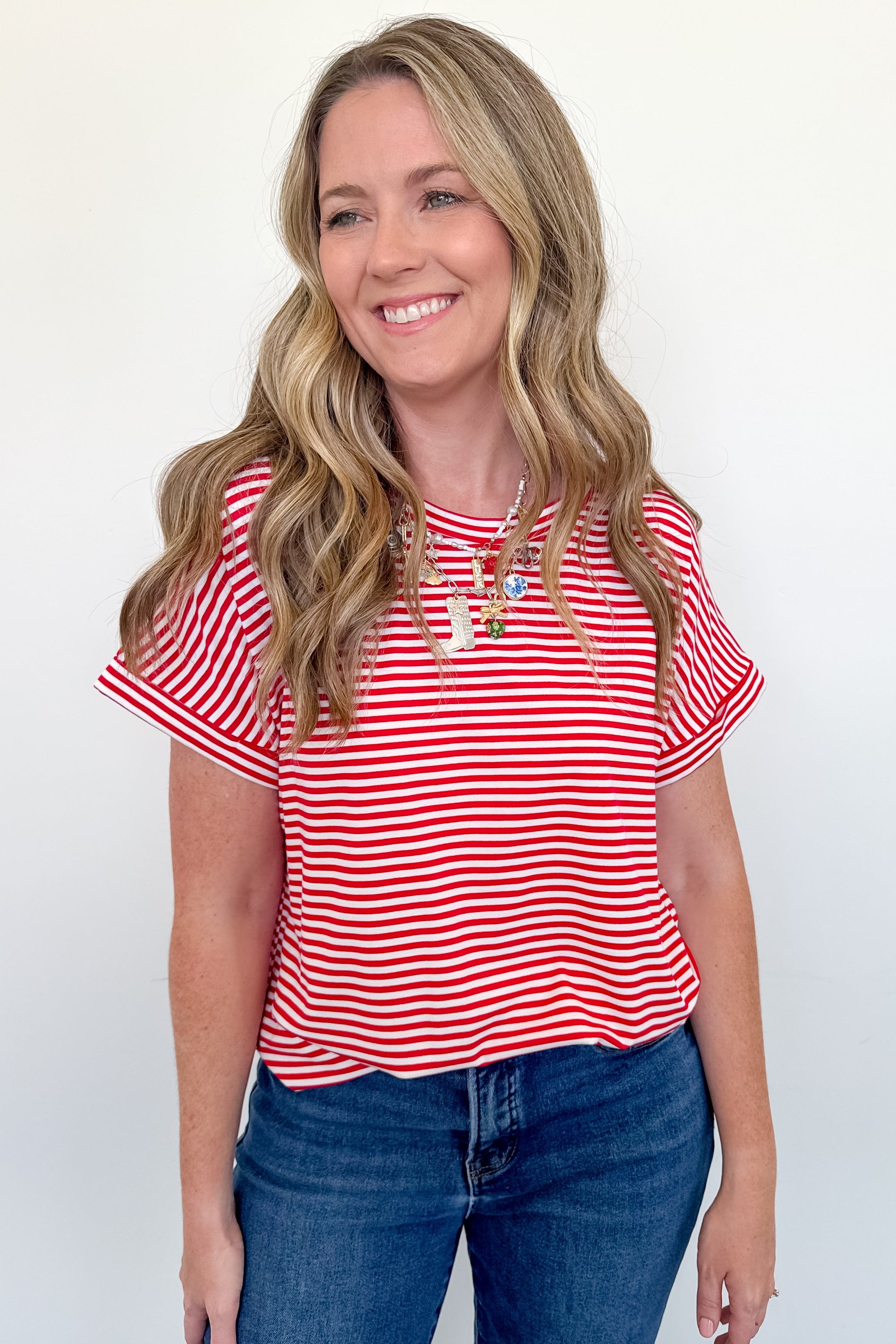 Woman wearing a red and white striped shirt and blue jeans against a white background