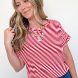 Woman wearing a red and white striped shirt with blue jeans on a plain background
