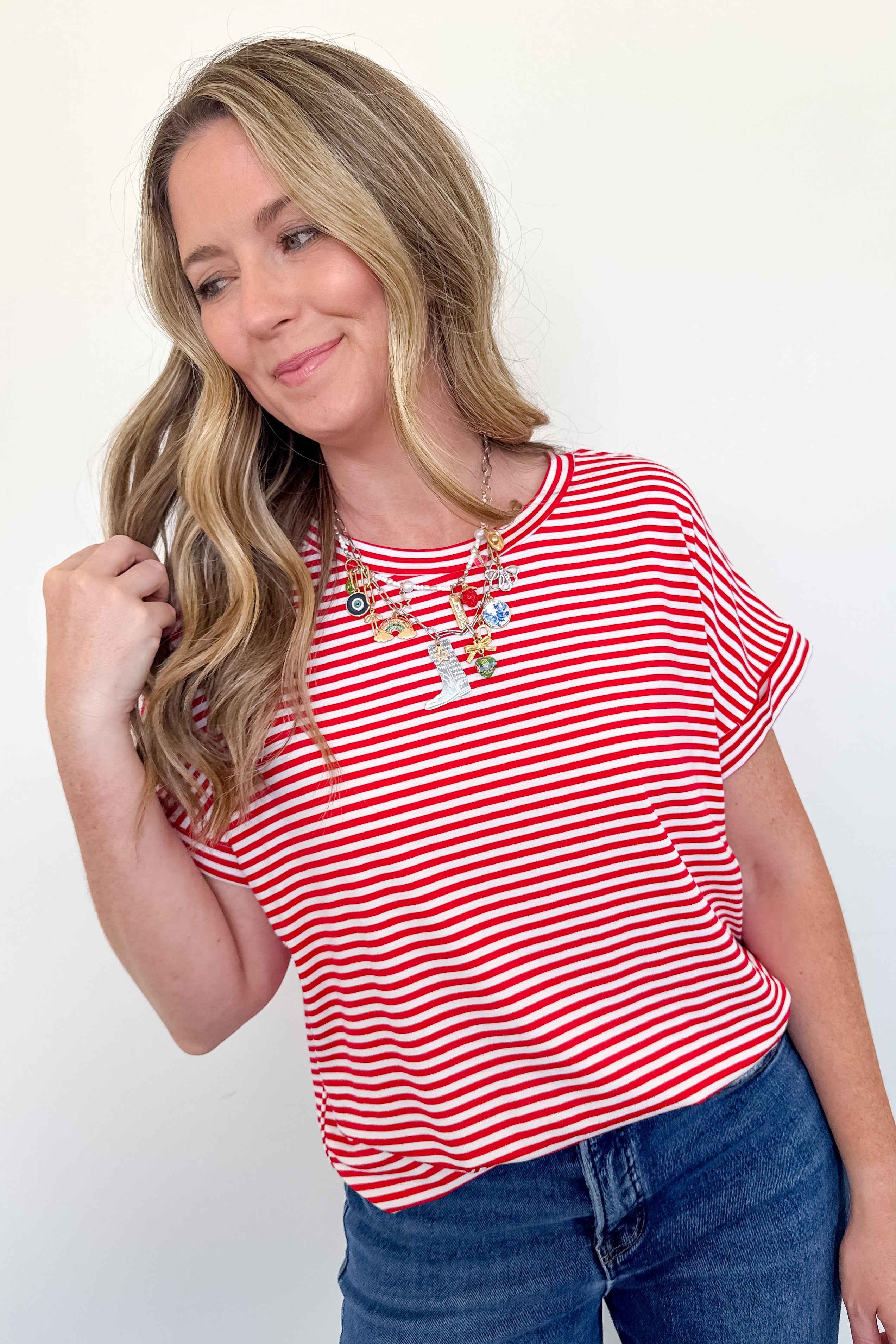 Woman wearing a red and white striped shirt with blue jeans on a plain background