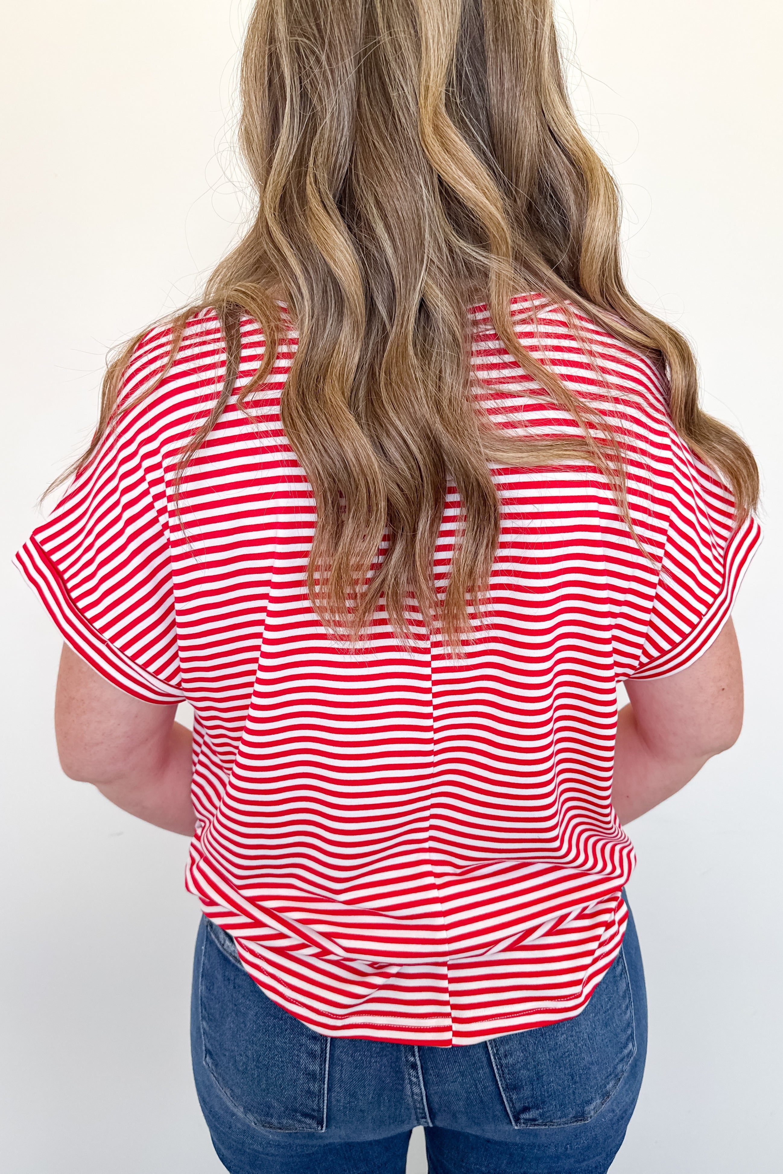 Person wearing a red and white striped shirt with blue jeans on a white background
