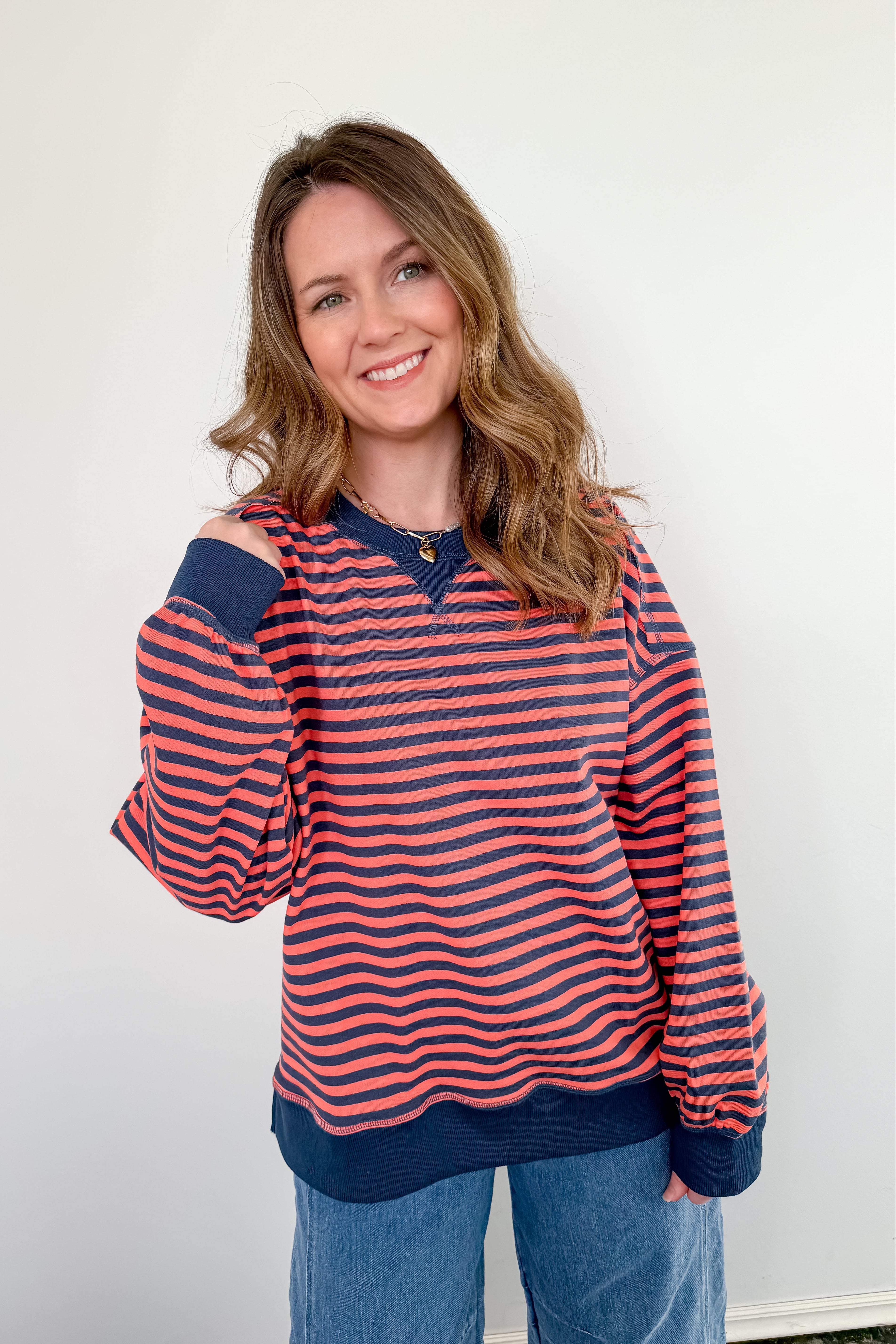 Woman wearing a red and navy striped sweater with blue jeans against a white background