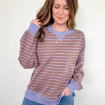 Woman wearing a striped long-sleeve shirt and jeans against a white wall