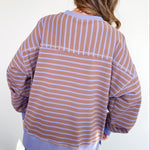 Person wearing a striped shirt and jeans against a white wall
