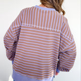 Person wearing a striped shirt and jeans against a white wall