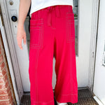 Woman wearing red pants with pockets and a tie waist.