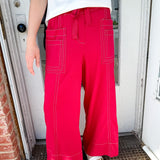 Woman wearing red pants with pockets and a tie waist.