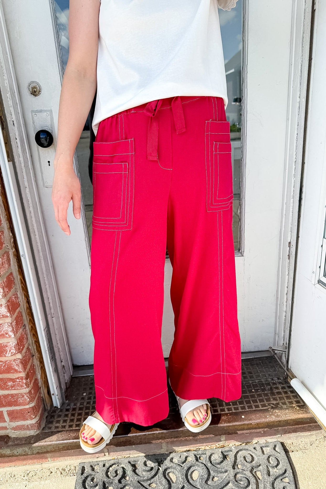 Woman wearing red pants with pockets and a tie waist.