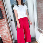 Woman in a white tee and red pants that are wide leg.