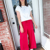 Woman in a white tee and red pants that are wide leg.