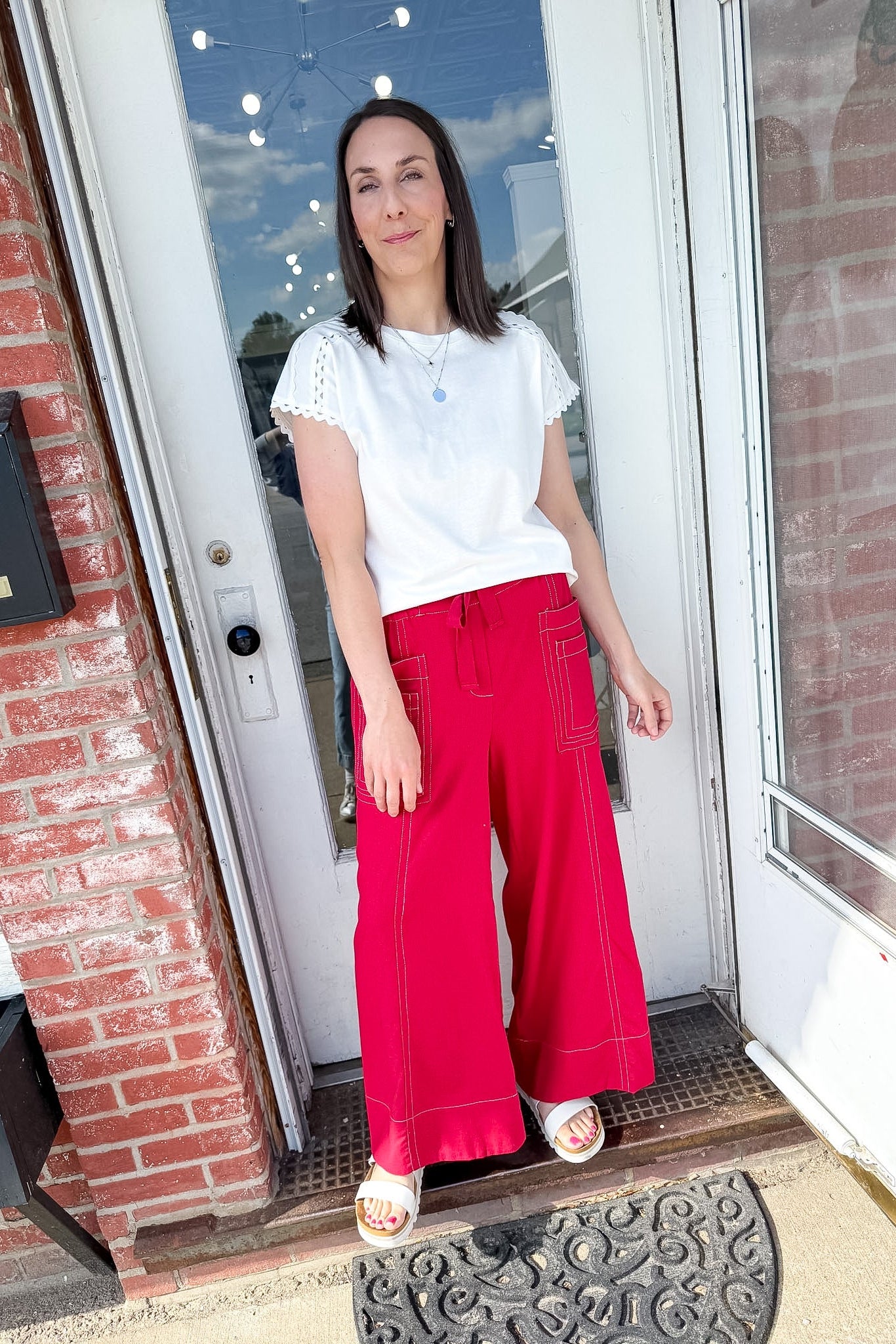 Woman in a white tee and red pants that are wide leg.