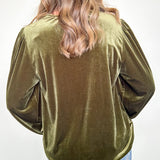 Person wearing an olive green velvet top with long sleeves against a white background