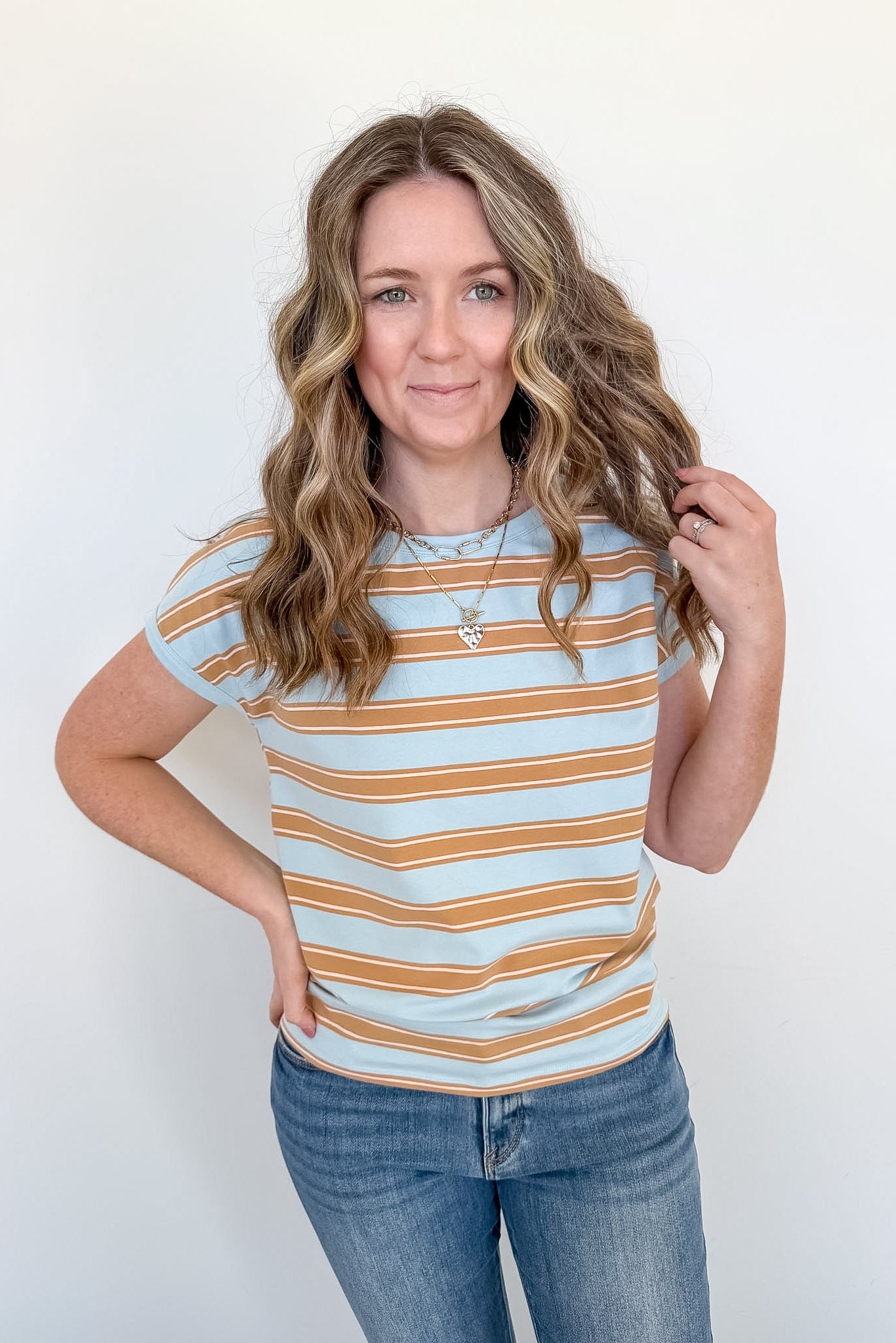 Woman wearing a striped shirt and jeans against a white background