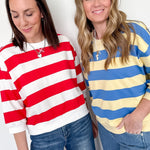 Two women wearing colorful striped sweaters against a white background