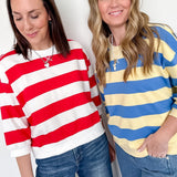 Two women wearing colorful striped sweaters against a white background