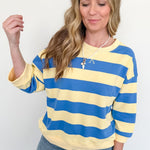 Woman wearing a yellow and blue striped sweater against a white background