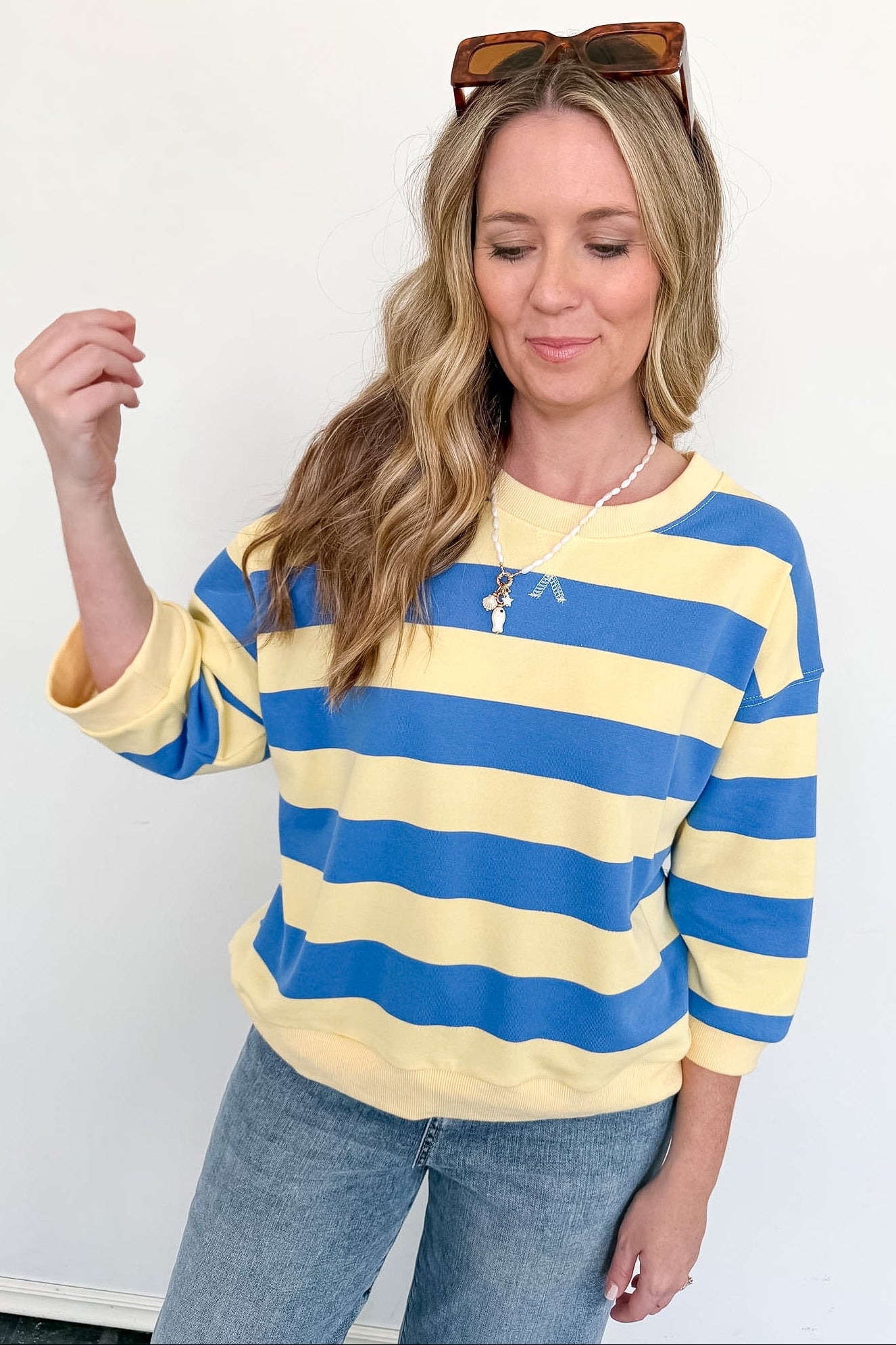 Woman wearing a yellow and blue striped sweater against a white background