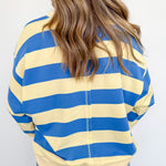 Person wearing a blue and yellow striped shirt with a plain background