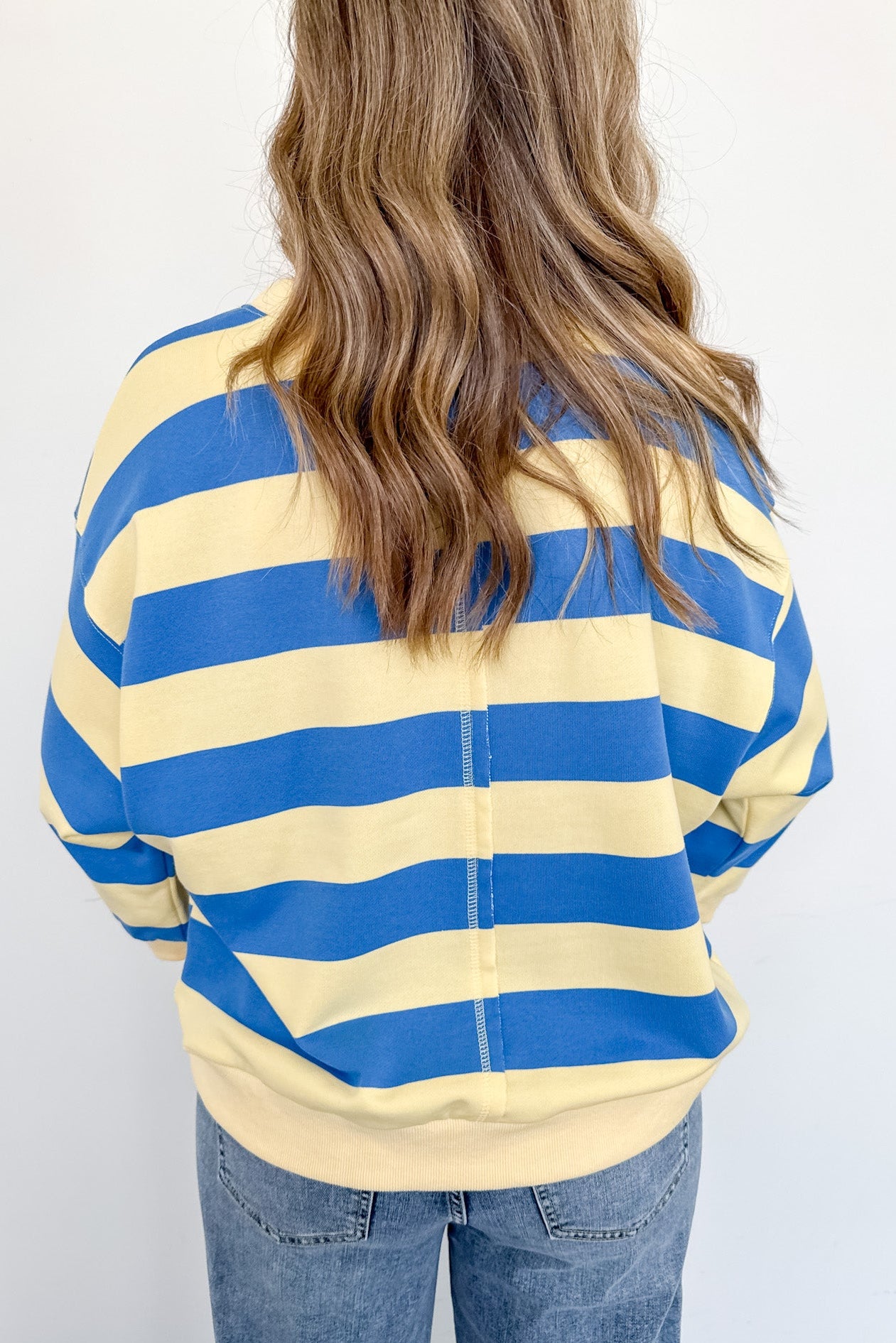 Person wearing a blue and yellow striped shirt with a plain background