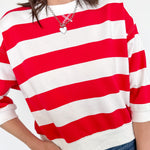 Person wearing a red and white striped shirt with a plain background