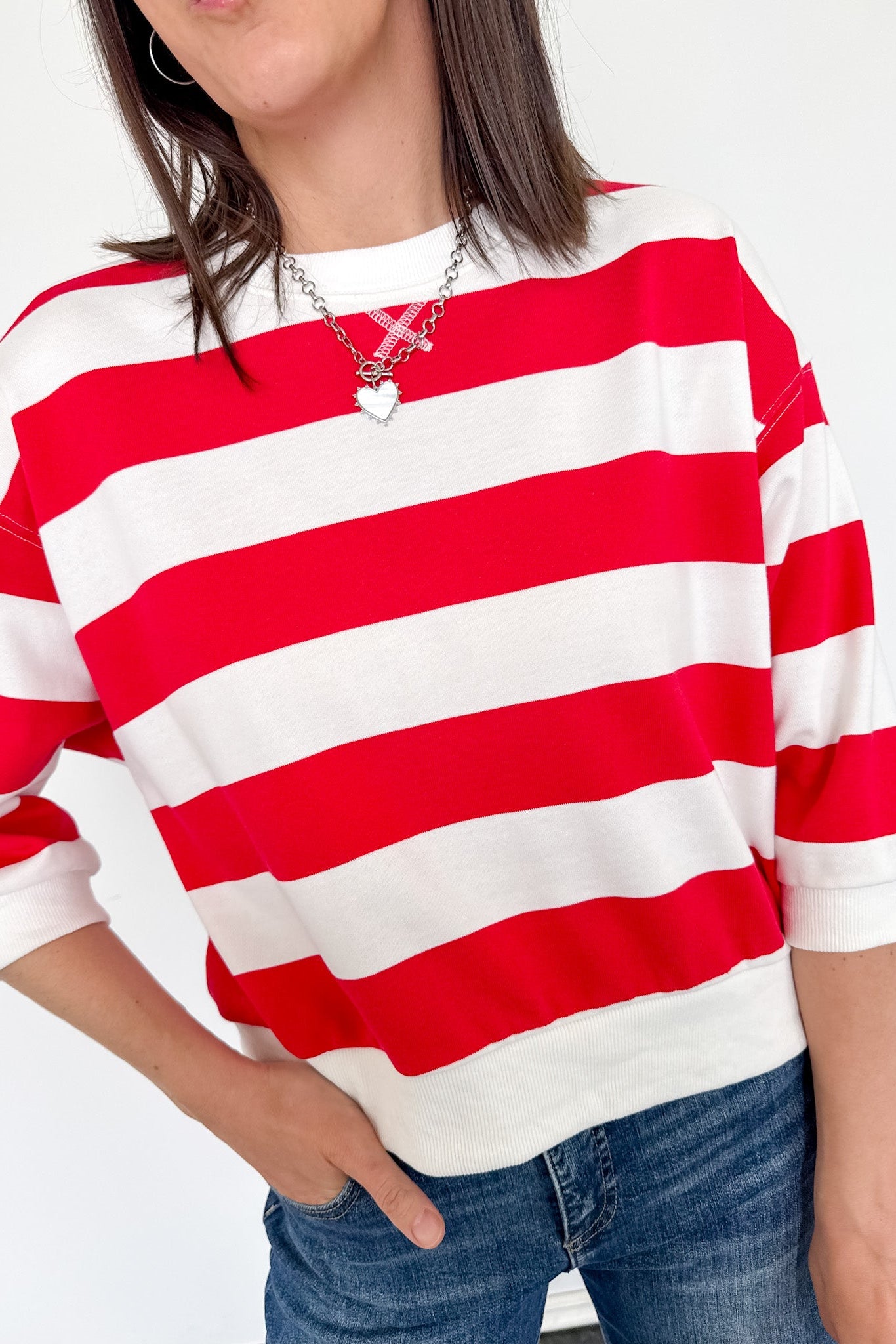 Person wearing a red and white striped shirt with a plain background