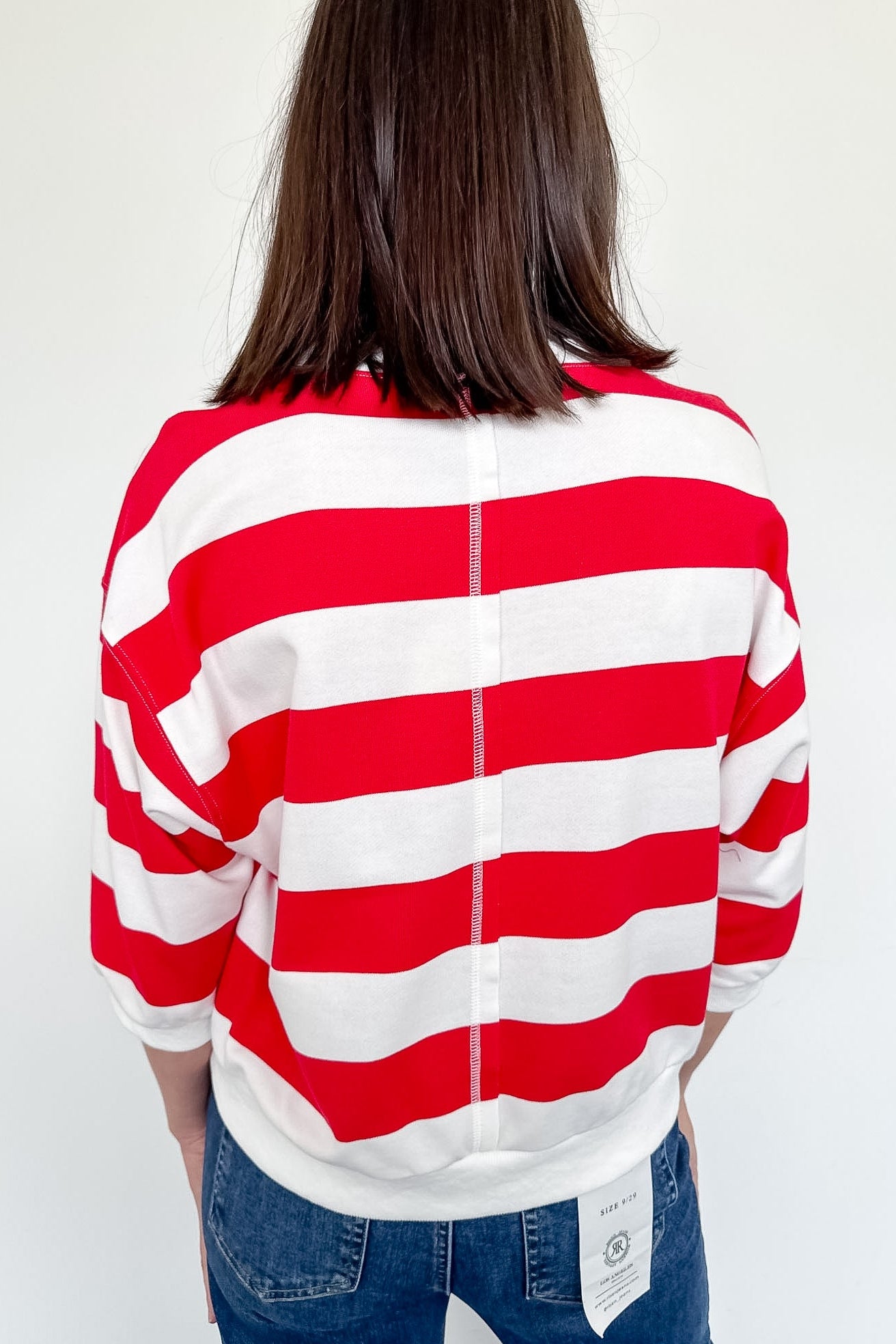 Person wearing a red and white striped shirt with a plain background
