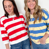 Two women wearing colorful striped sweaters against a white background