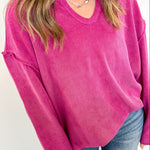 Person wearing a bright pink sweater and blue jeans against a white background