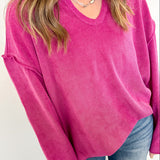 Person wearing a bright pink sweater and blue jeans against a white background