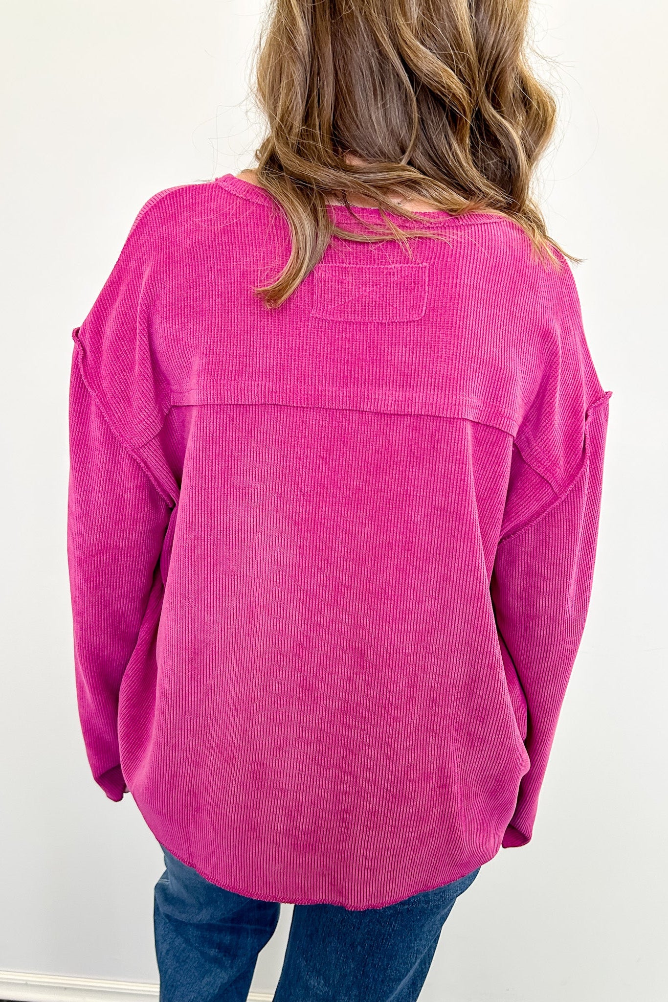 Person wearing a pink corduroy shirt with a white background