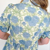 Person wearing a floral shirt with blue and green flowers on a white background