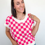 Woman wearing a pink and white checkered top with a plain background