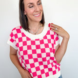 Woman wearing a pink and white checkered top with a plain background