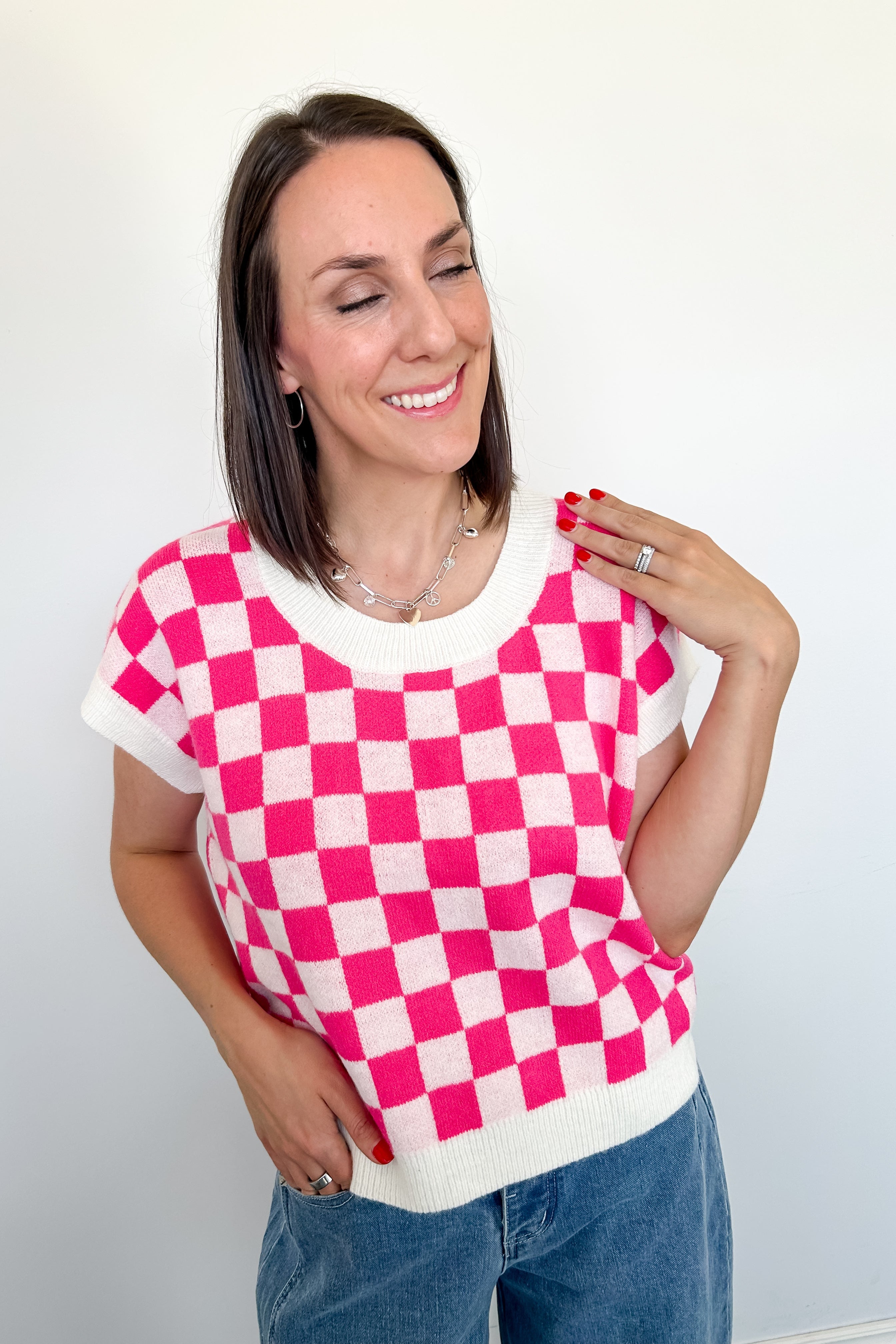 Woman wearing a pink and white checkered top with a plain background