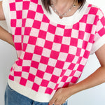 Person wearing a pink and white checkered top with blue jeans against a white background
